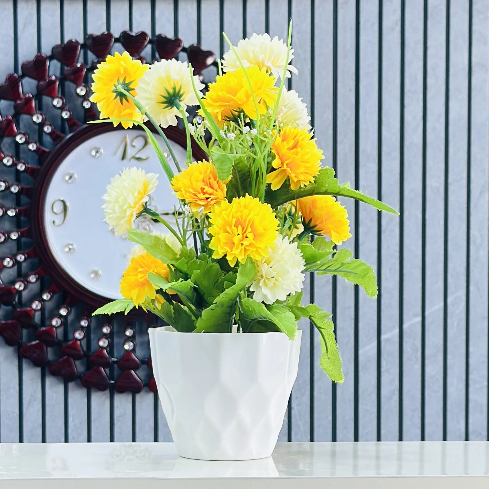 an artificial flower arrangement in a white pot.