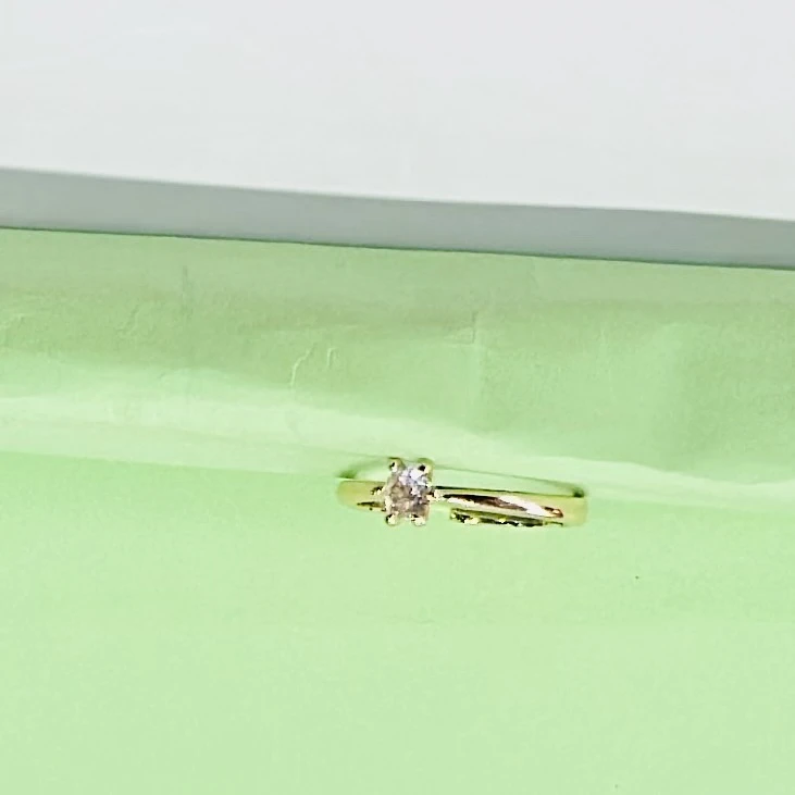 Gold solitaire engagement ring with a single round clear gemstone.