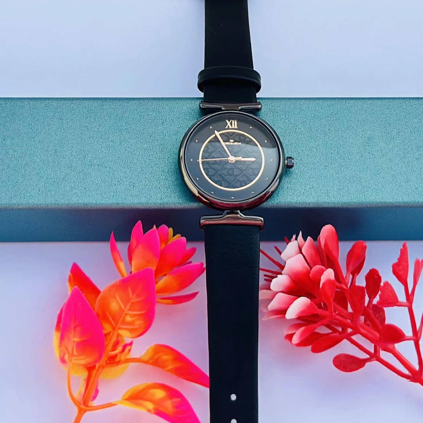Analog watch for women with a black leather strap and gunmetal dial.