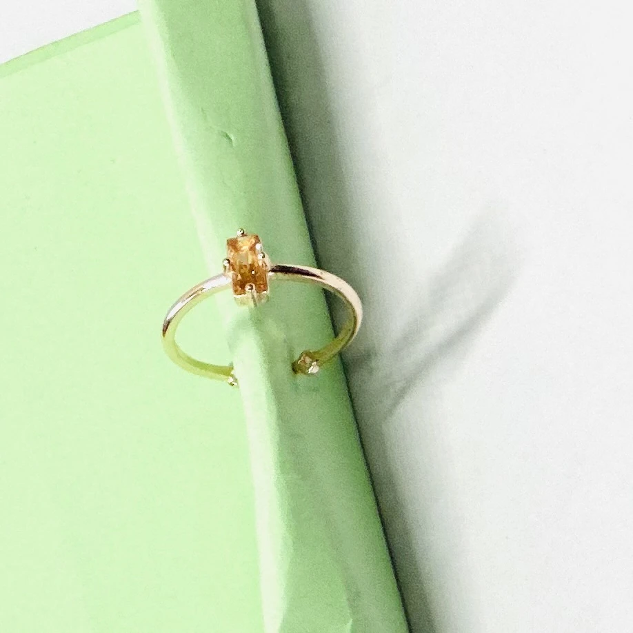 An emerald-cut imperial topaz or citrine solitaire ring in 14k gold.
