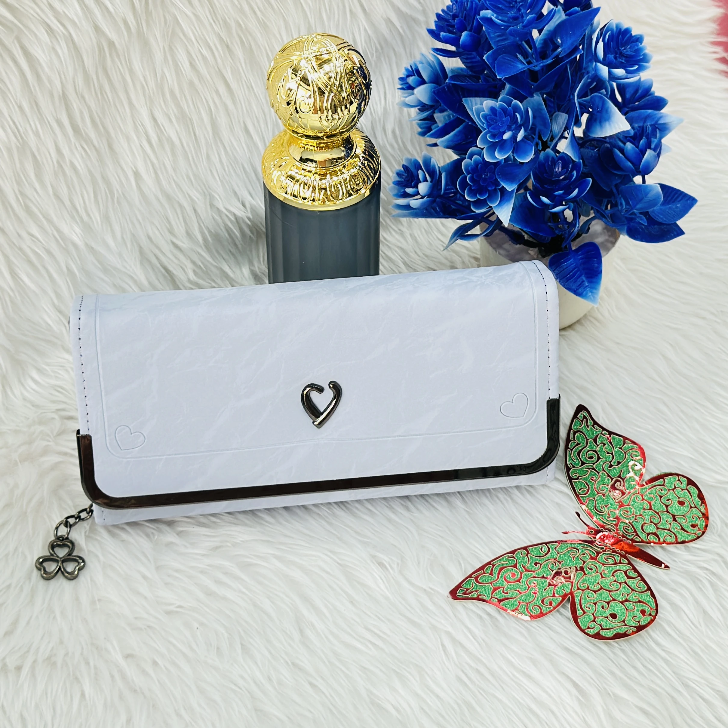 white faux leather clutch wallet featuring a small heart-shaped charm