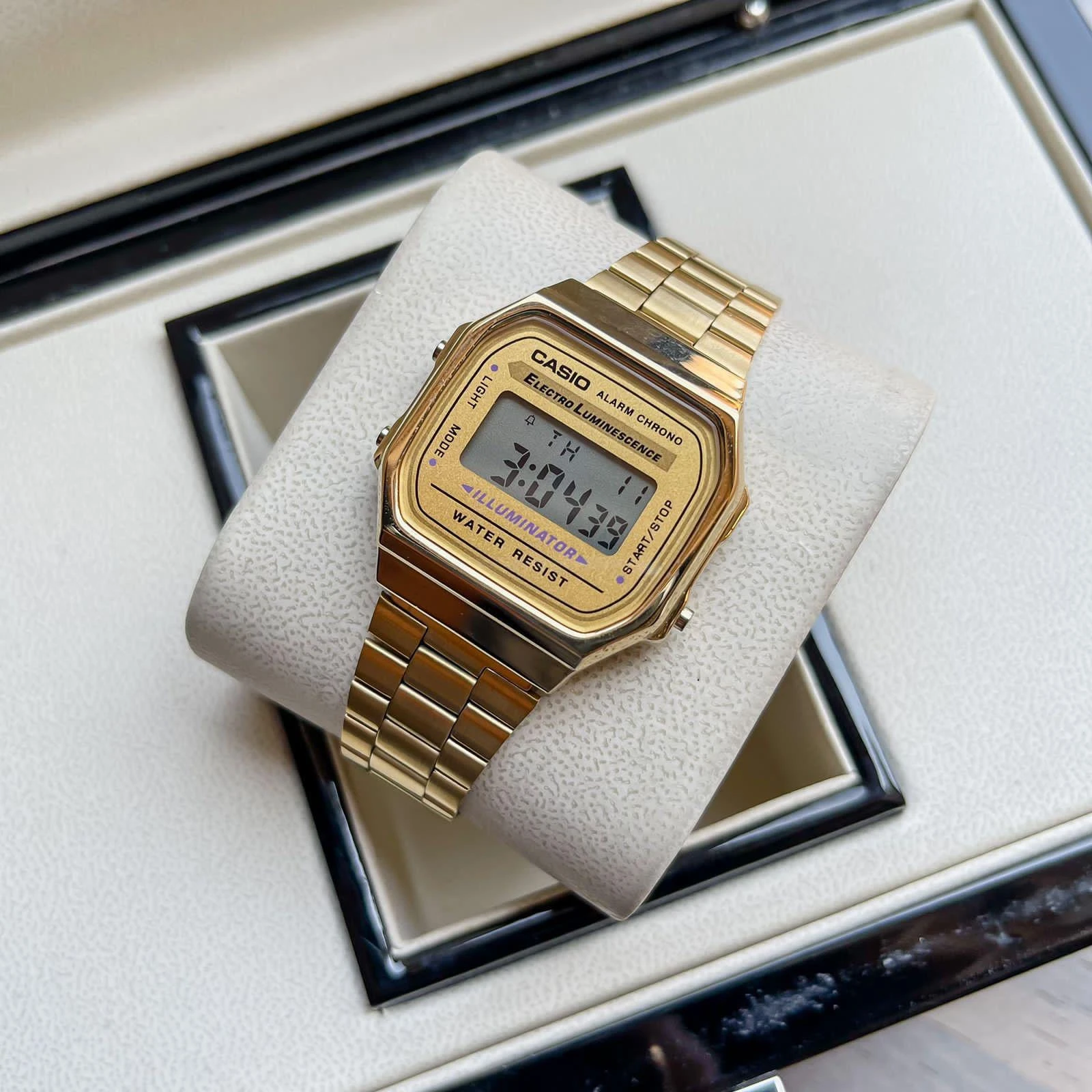 Digital watch with a gold-tone case and stainless steel band.