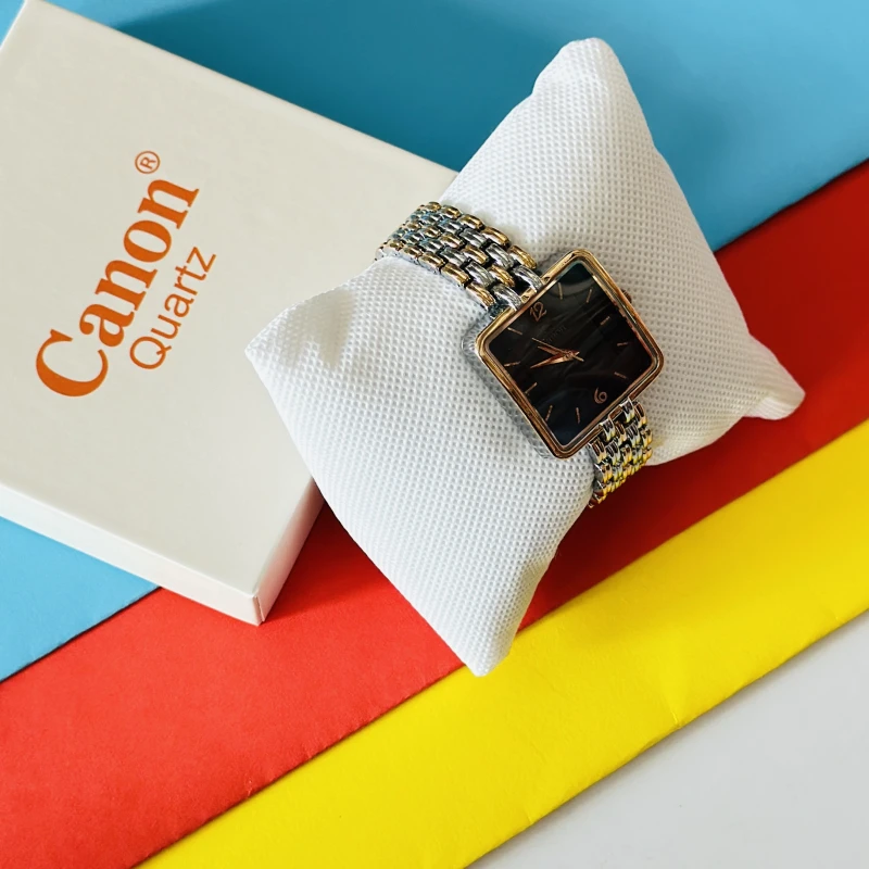 women's analog wristwatch with a square black dial and a dual-tone metallic link bracelet, resting on a white display cushion.