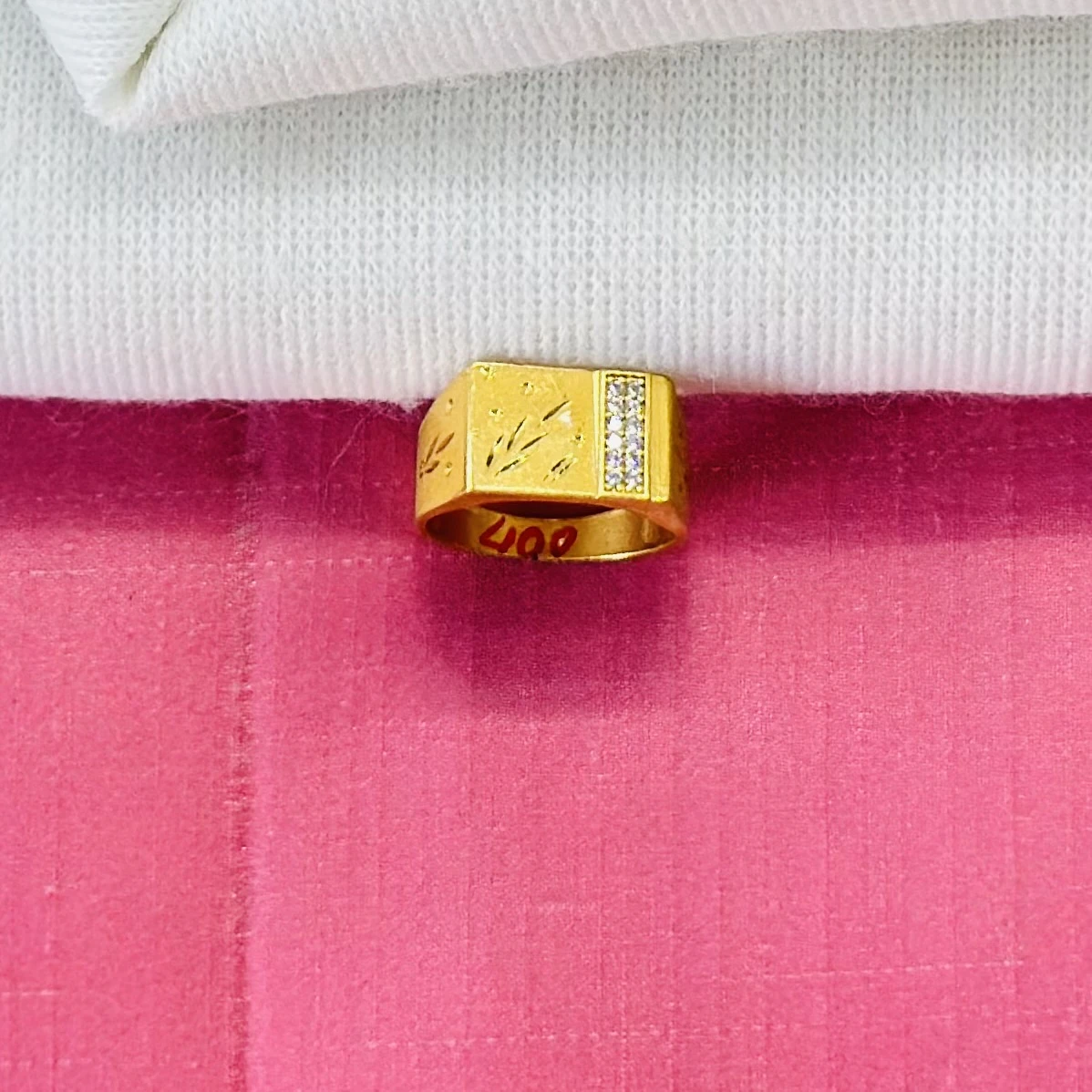 An engraved gold-toned men's ring with small white stones.