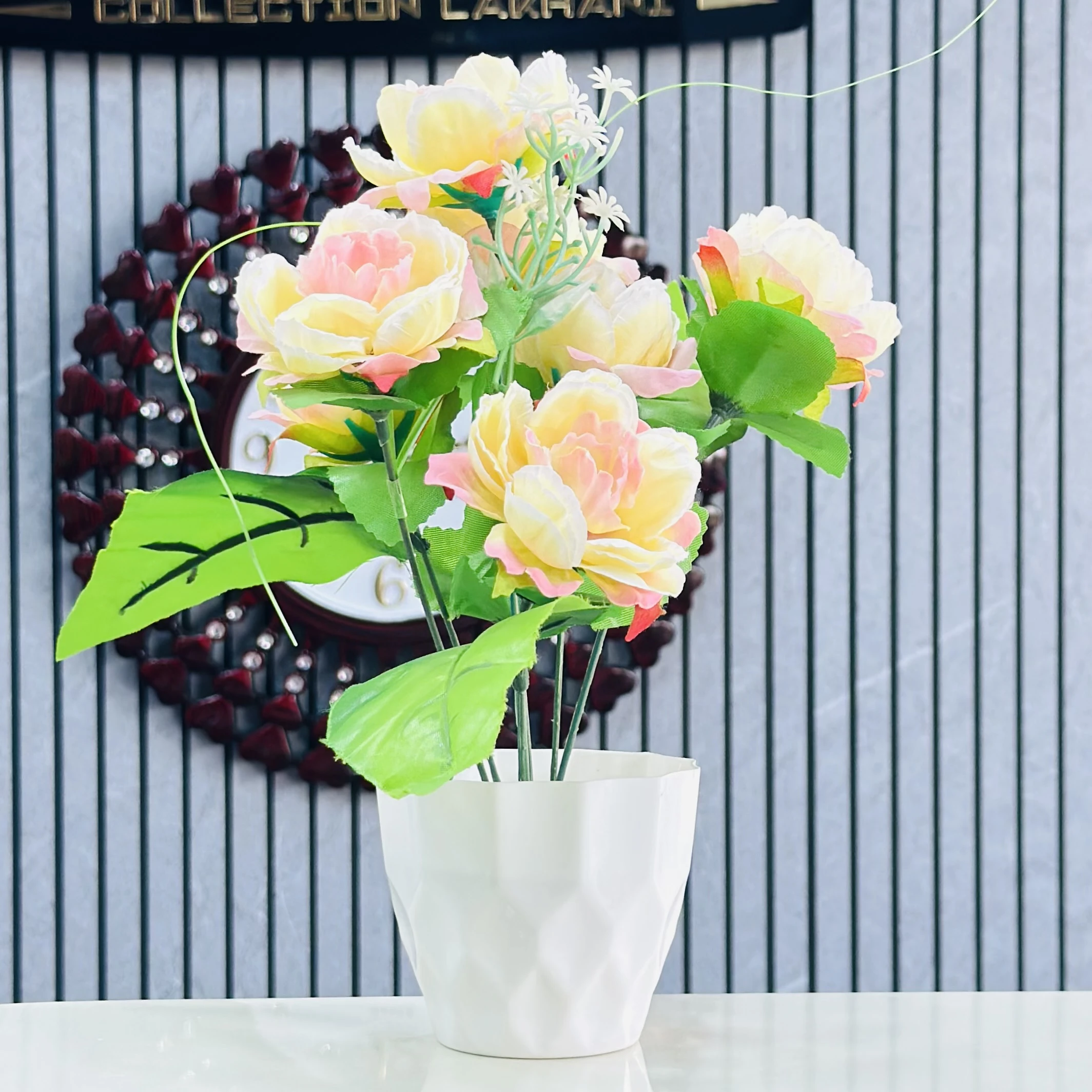 An artificial flower arrangement in a white ceramic pot.