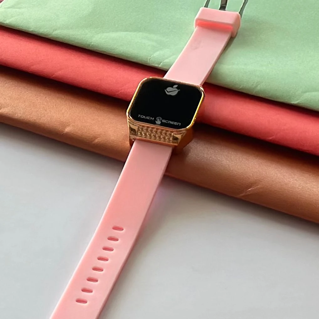 pink silicone strap and a gold-toned square dial.