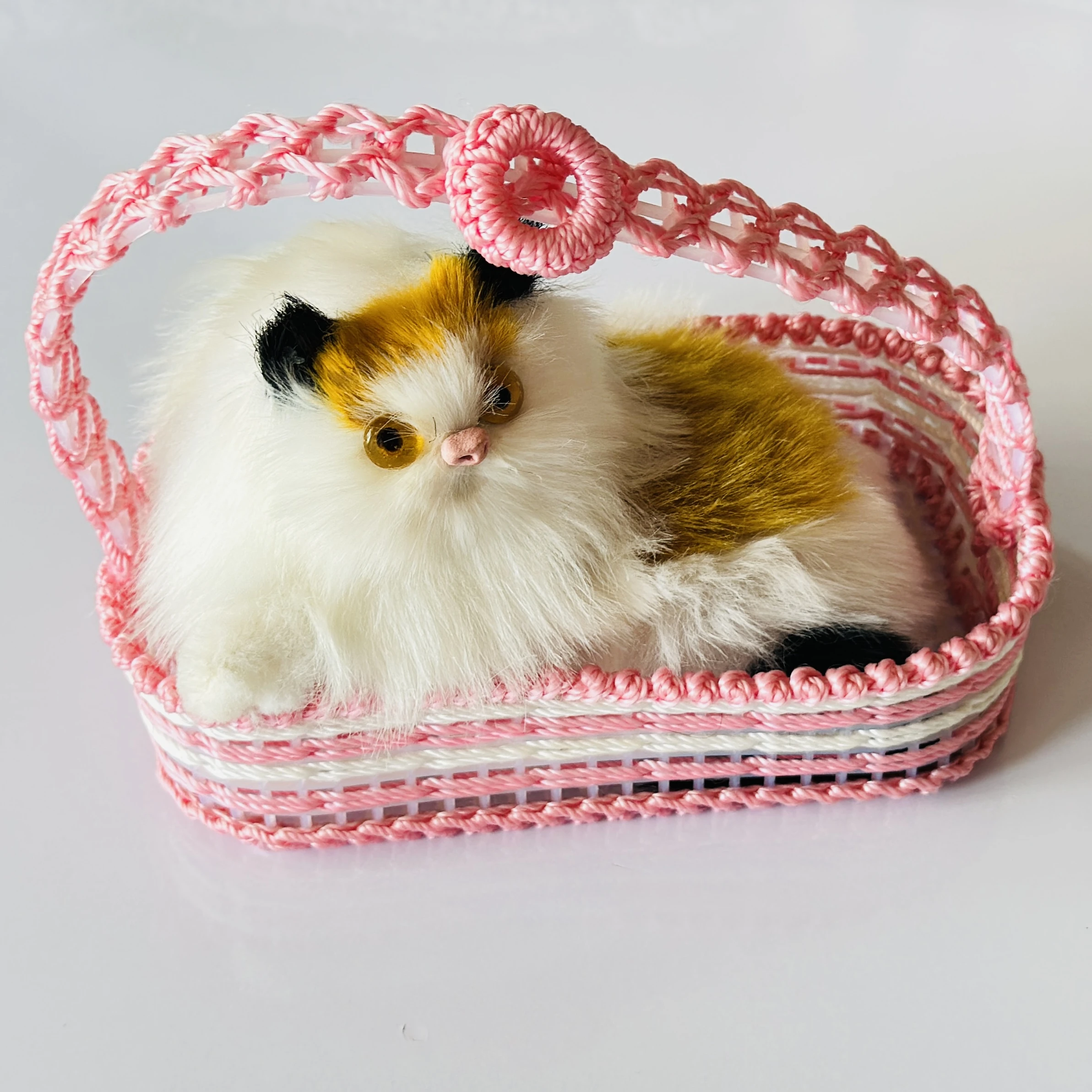 Decorative showpiece featuring a plush cat sitting inside a pink woven basket