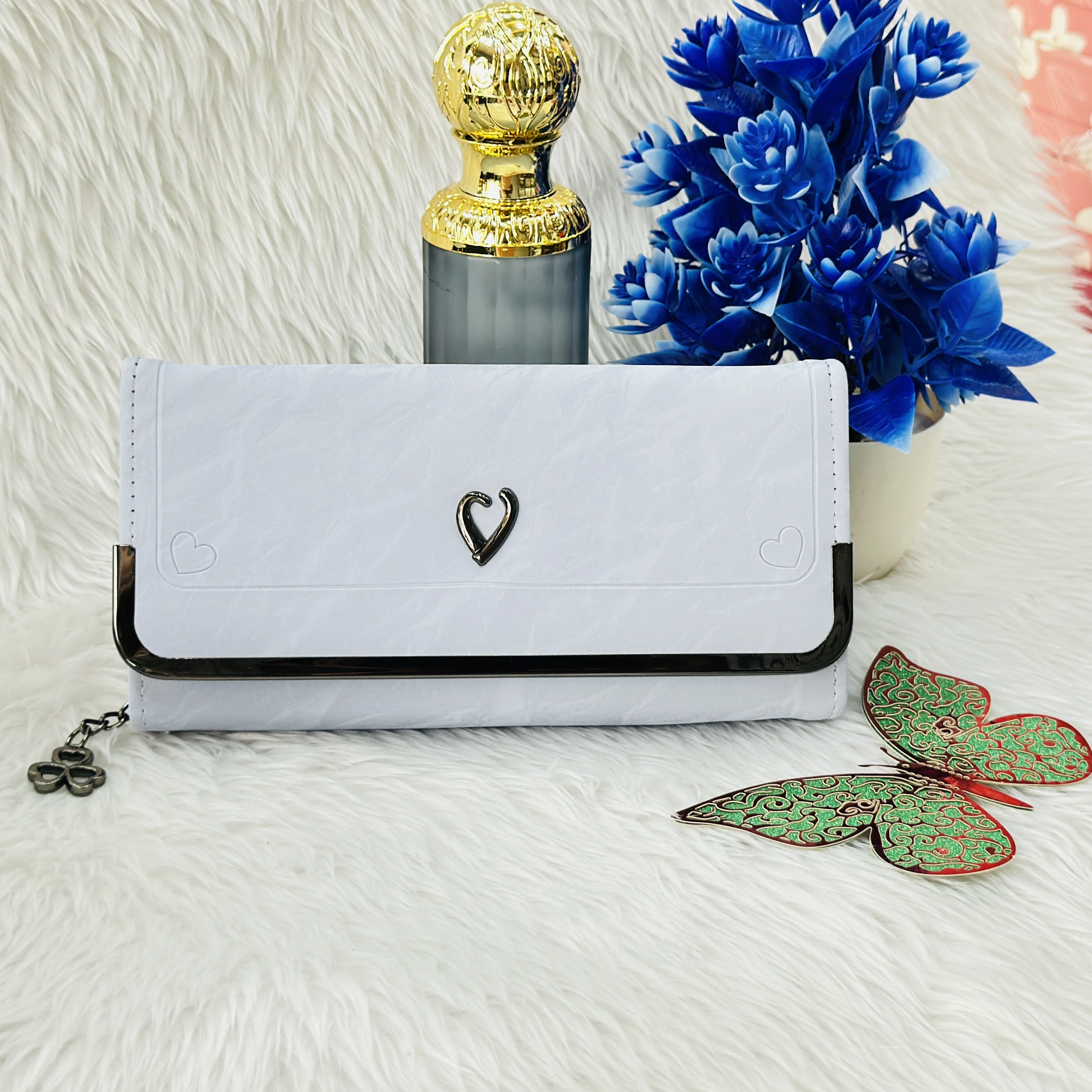 white faux leather clutch wallet featuring a small heart-shaped charm