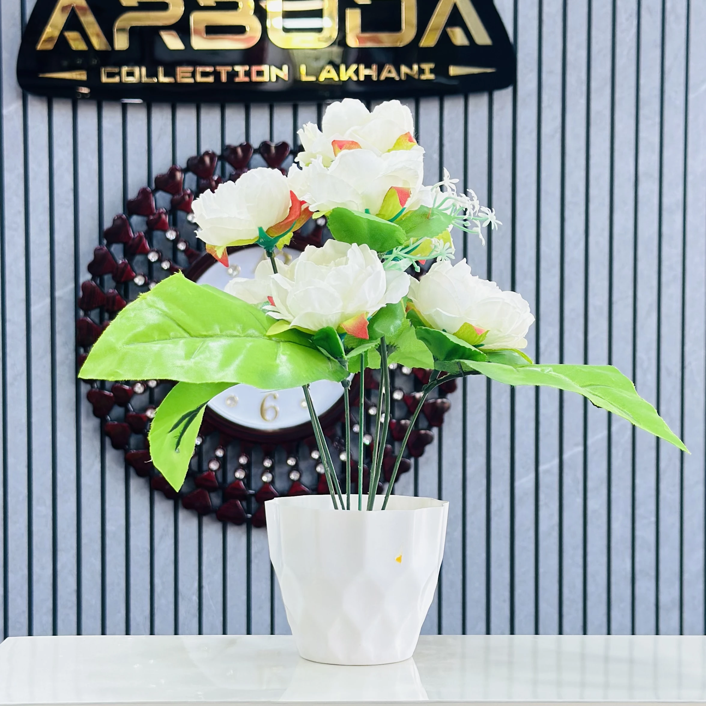 Lotus flower arrangement in a white geometric pot.