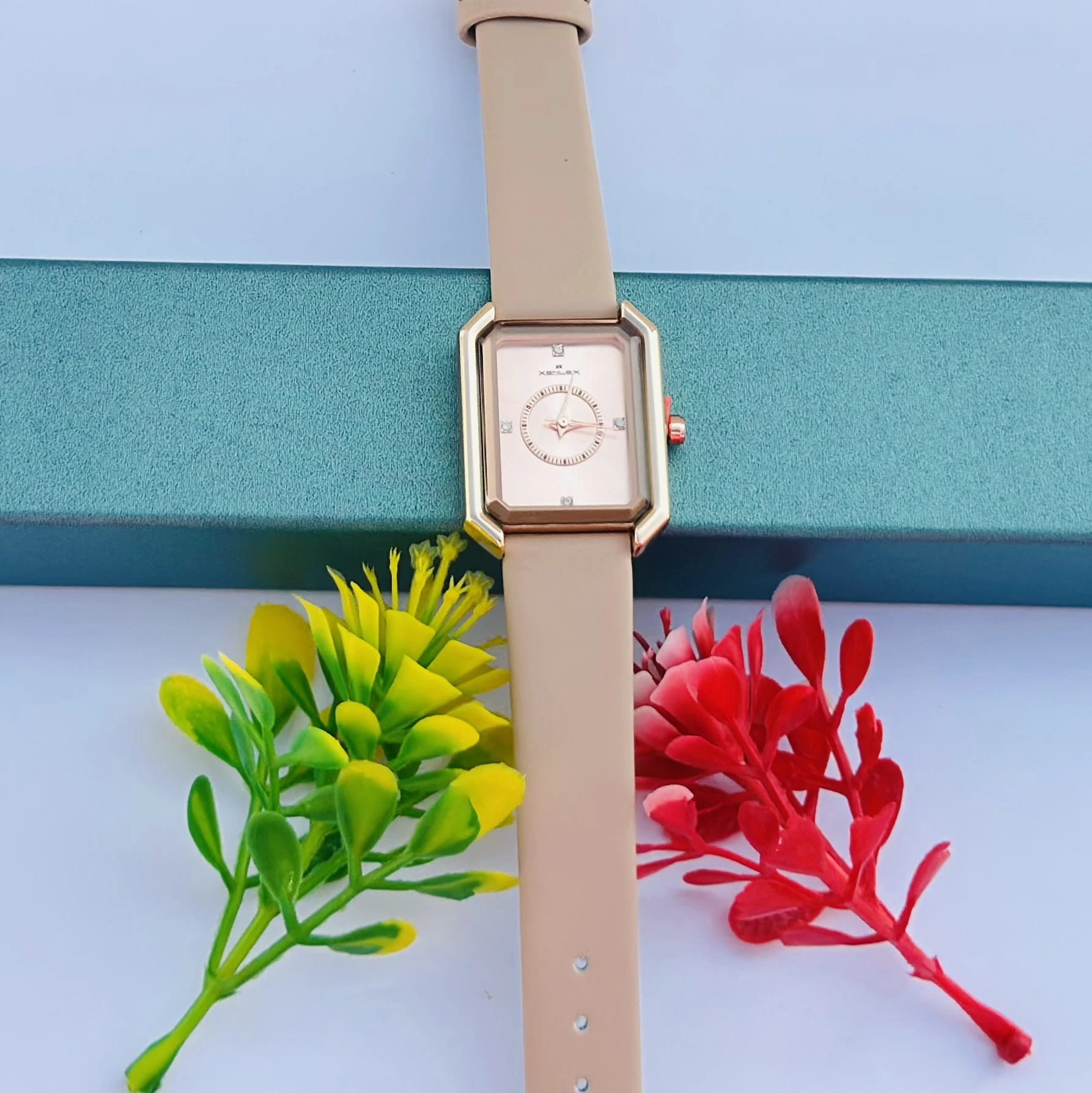 analog watch with a rectangular rose gold-toned case and a beige or light brown strap