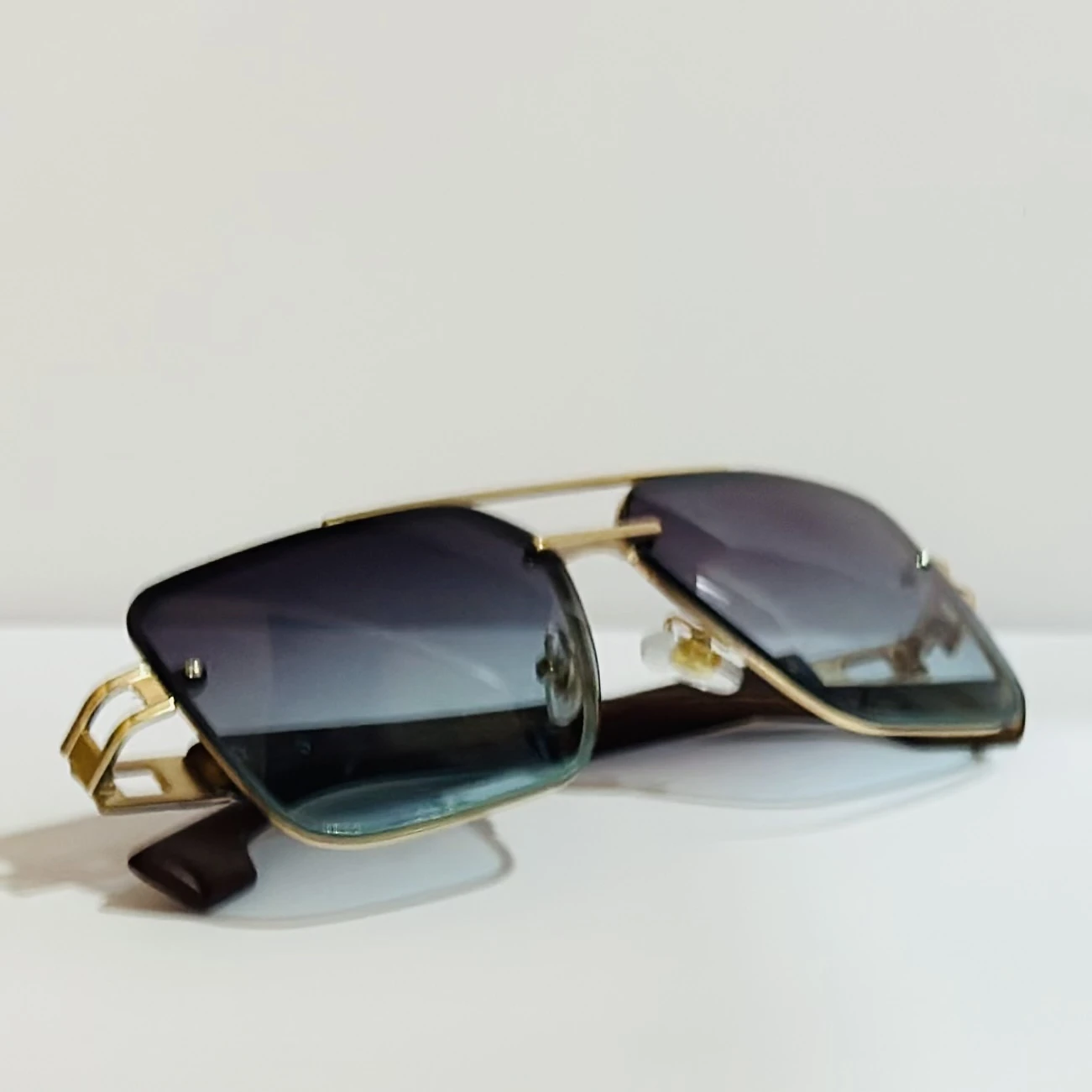 Pair of of aviator-style sunglasses with a gold-tone metal frame and blue gradient lenses.