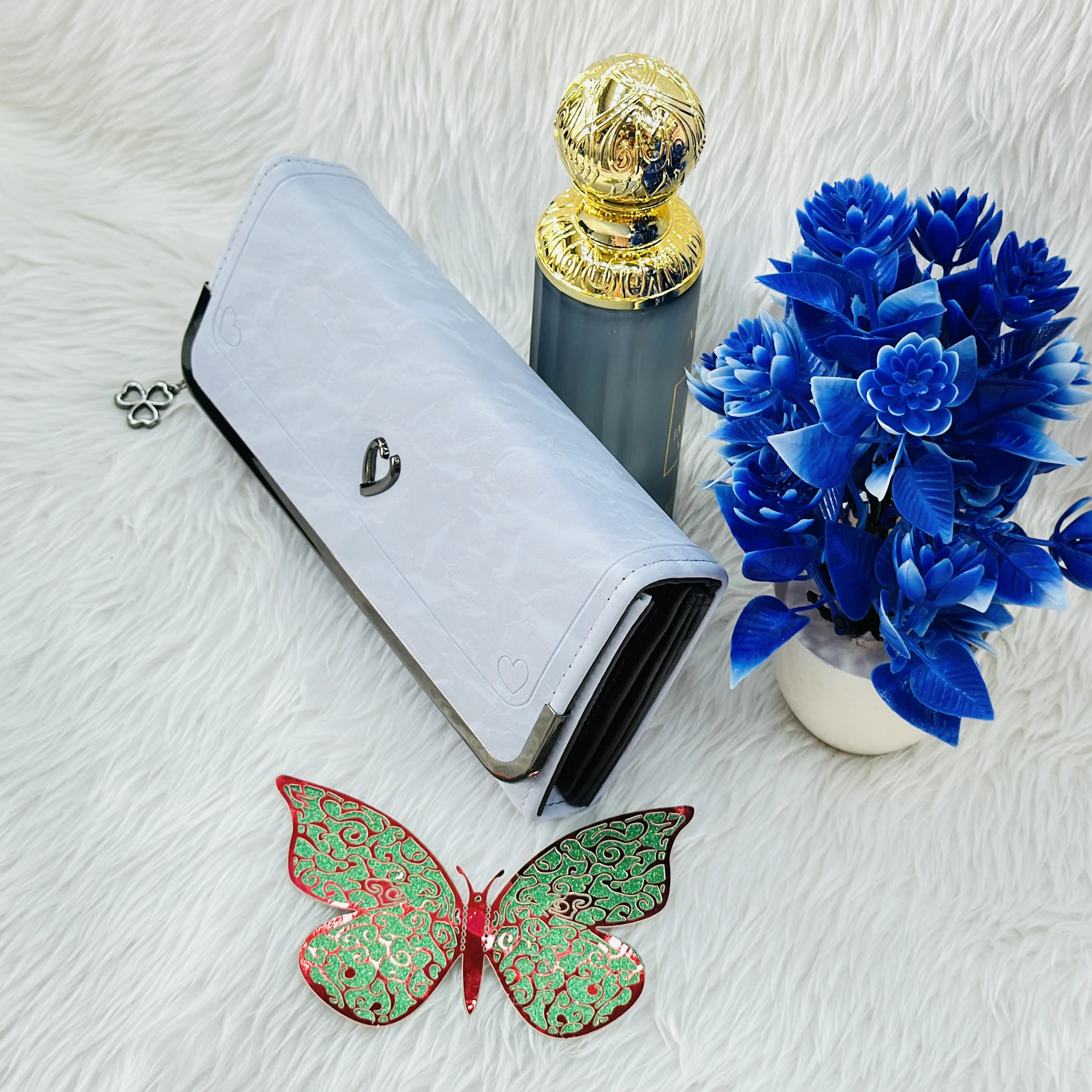 white faux leather clutch wallet featuring a small heart-shaped charm