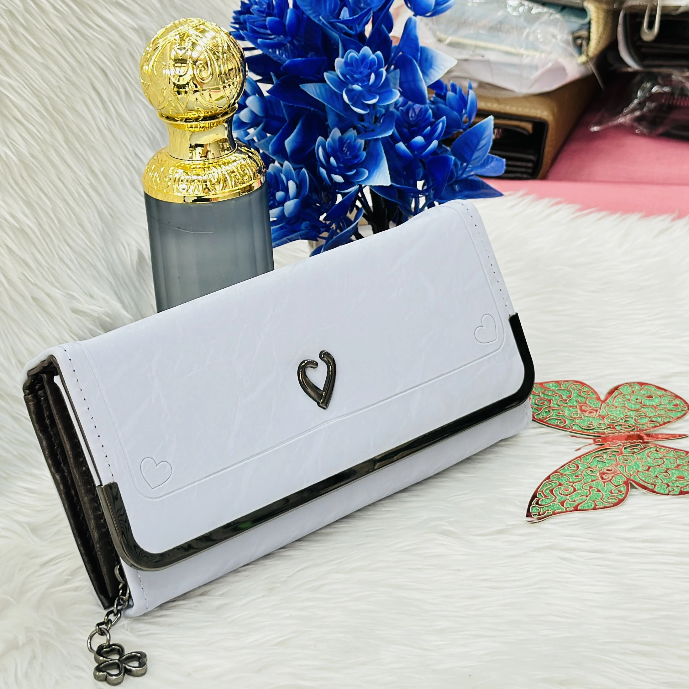 white faux leather clutch wallet featuring a small heart-shaped charm