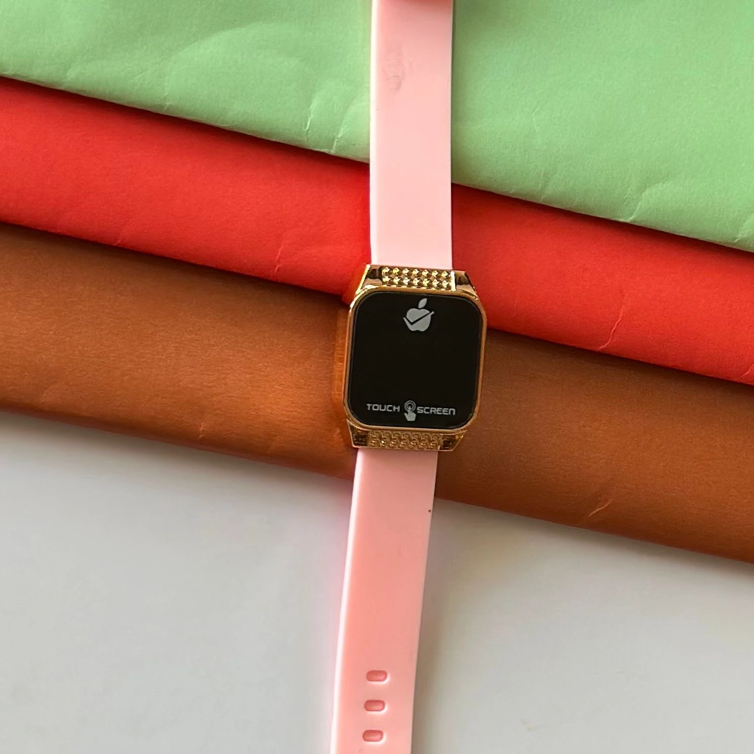 pink silicone strap and a gold-toned square dial.
